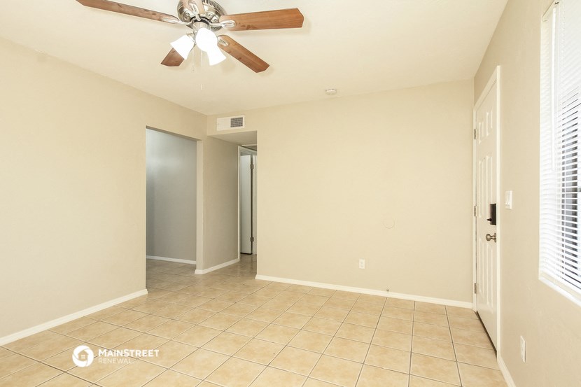an empty living room with a ceiling fan and tiled floor