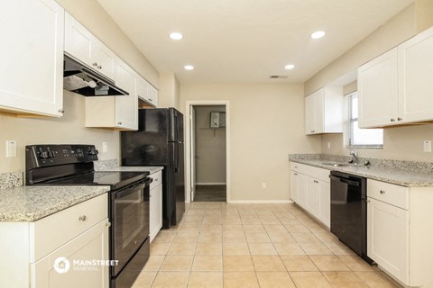a kitchen with white cabinets and black appliances