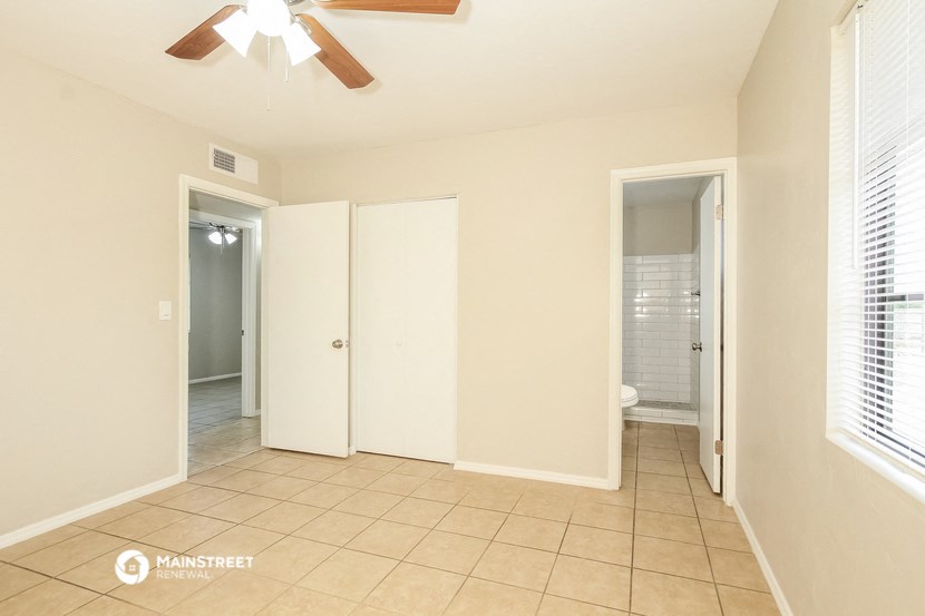 a living room with a ceiling fan and a door to a bathroom