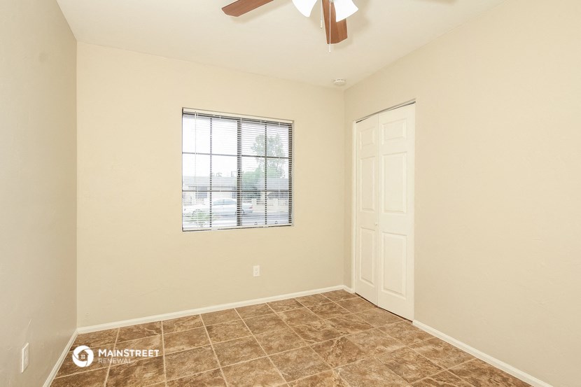 the spacious living room of a home with a window and a ceiling fan
