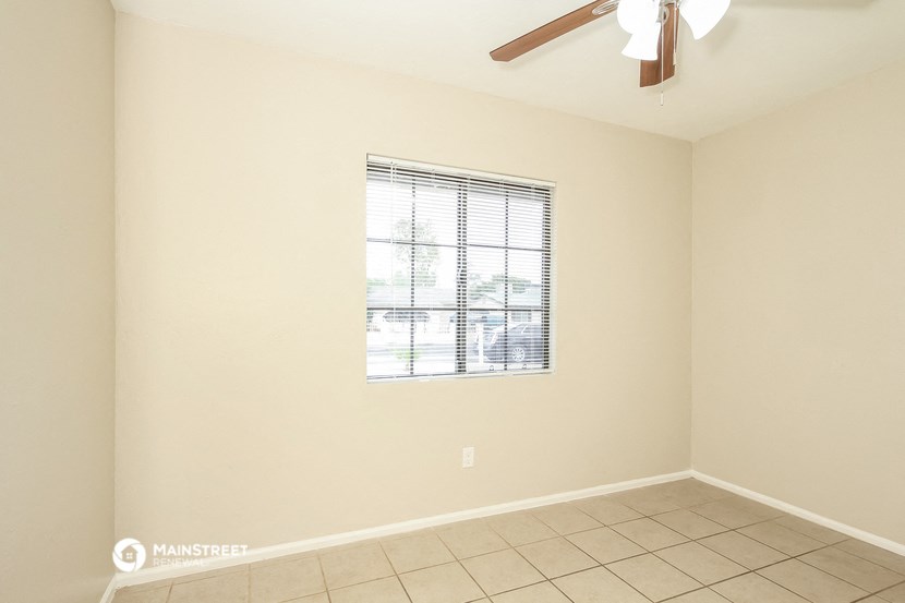 an empty living room with a window and a ceiling fan