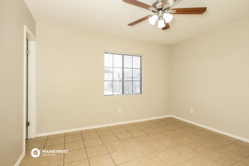 an empty living room with a ceiling fan and tiled floor