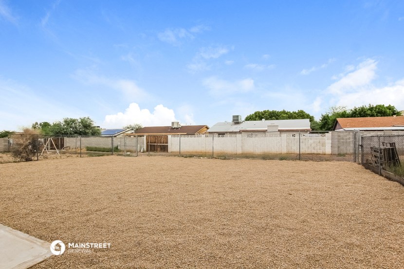 a large yard with a fence and a house in the background