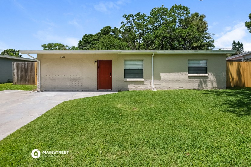 a white brick house with a yard and a red door