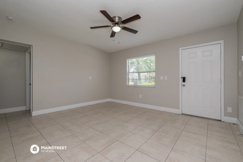 the spacious living room with ceiling fan and tiled floor