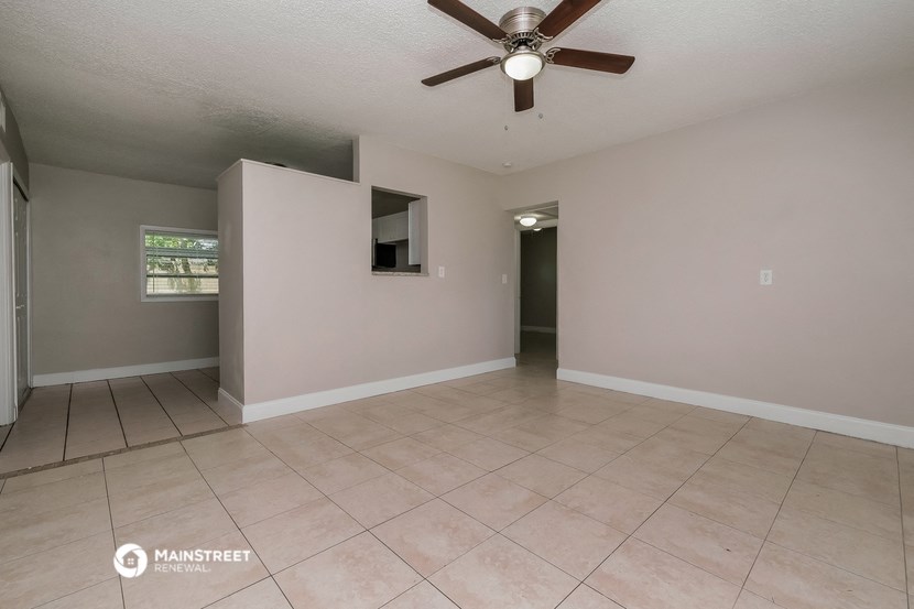 the living room of an empty house with a ceiling fan