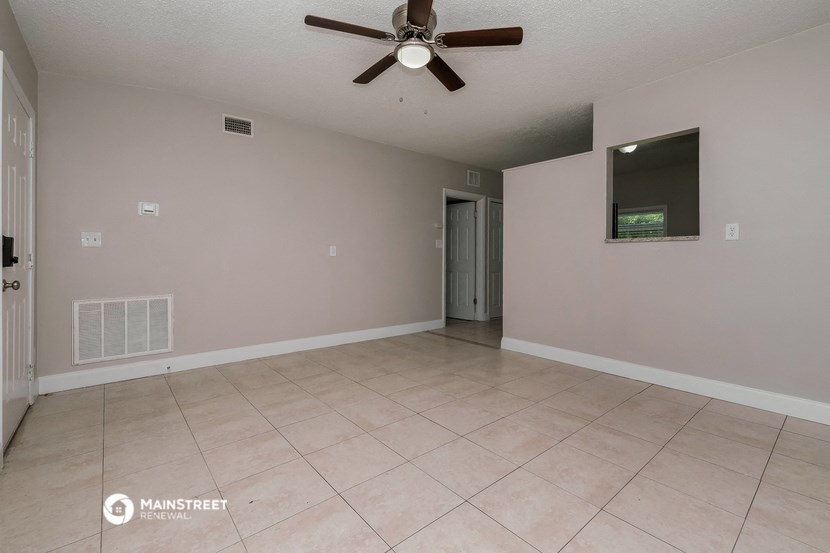 the living room of an empty house with a ceiling fan