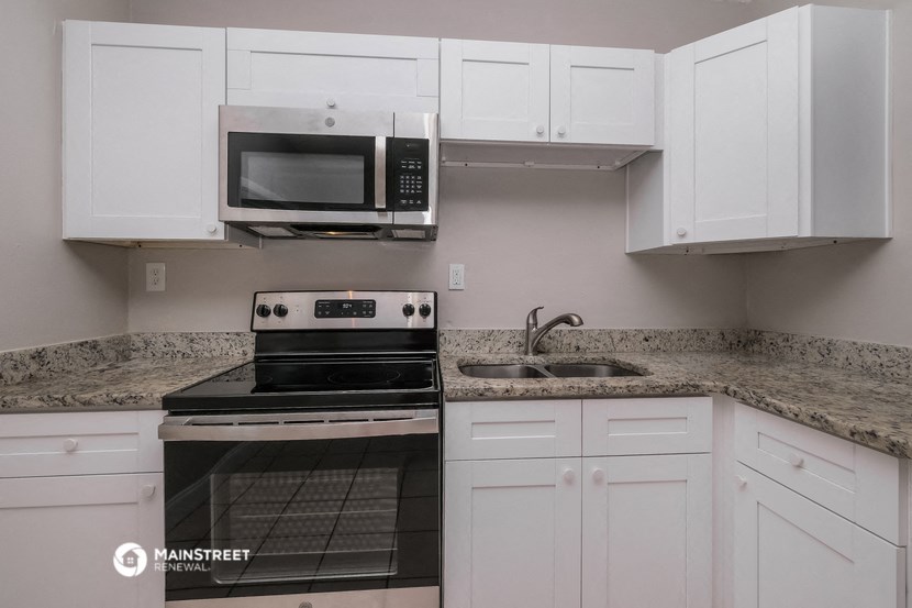 a kitchen with white cabinets and black appliances and granite counter tops