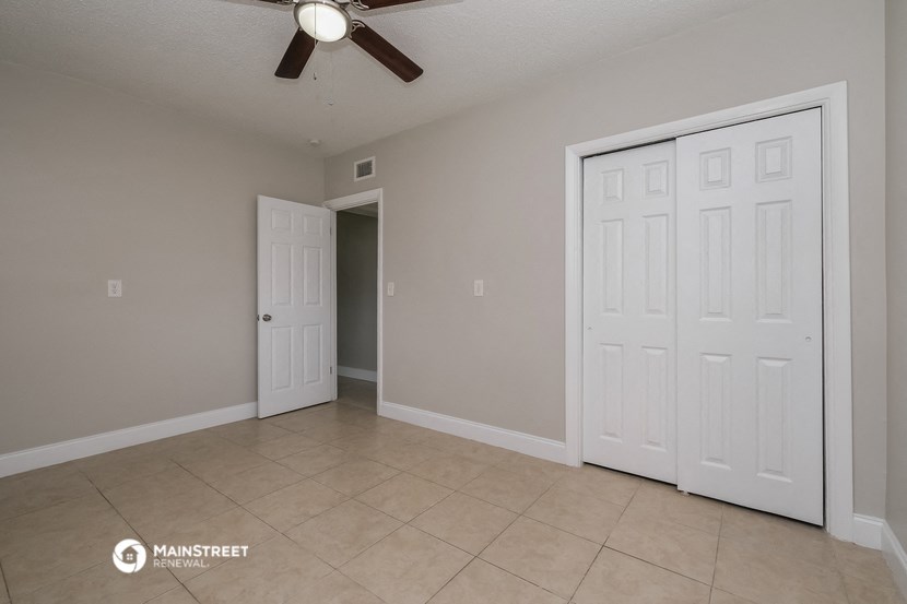 the spacious living room with two closets and a ceiling fan