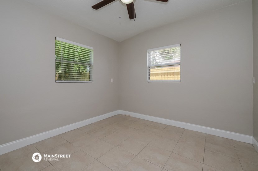 an empty room with two windows and a ceiling fan