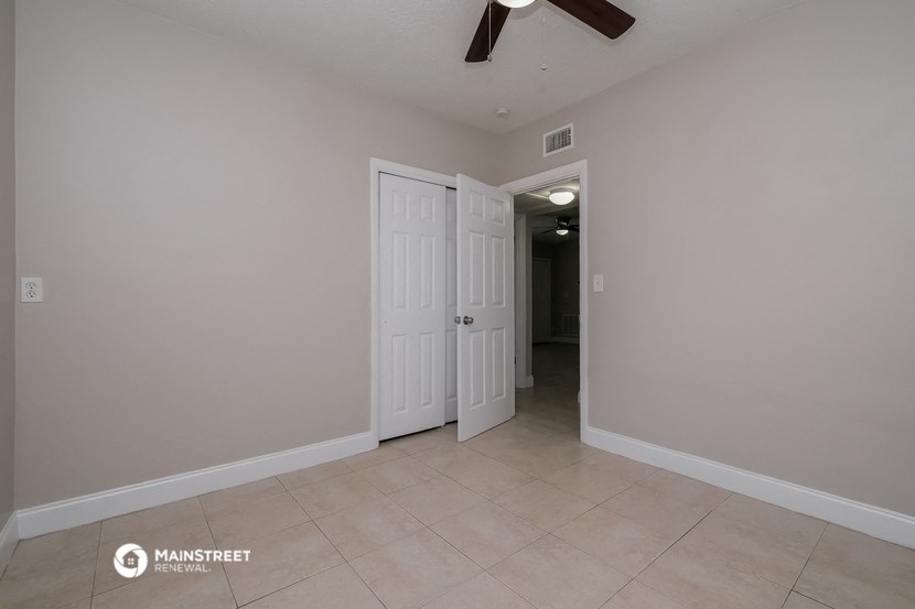 a living room with two doors and a ceiling fan