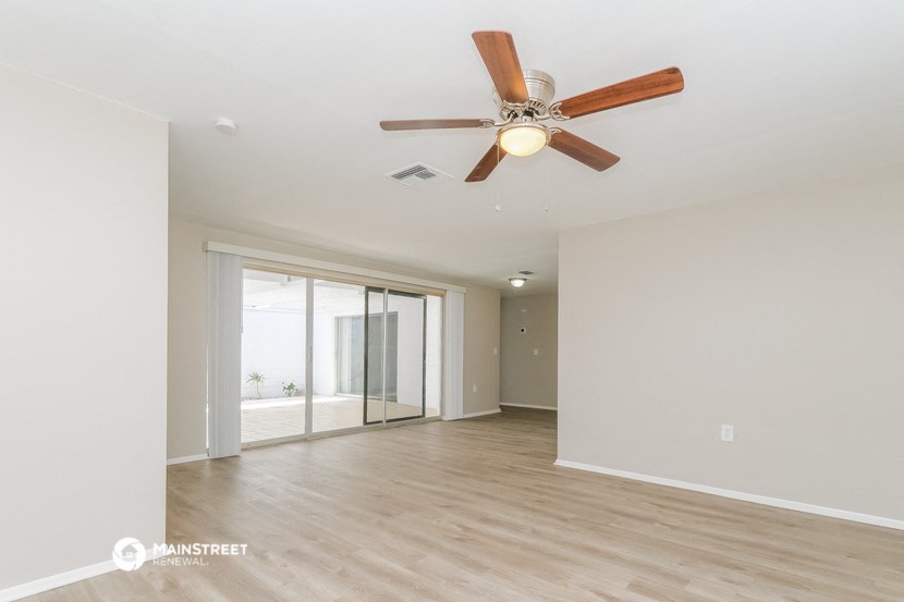 a living room with white walls and a ceiling fan
