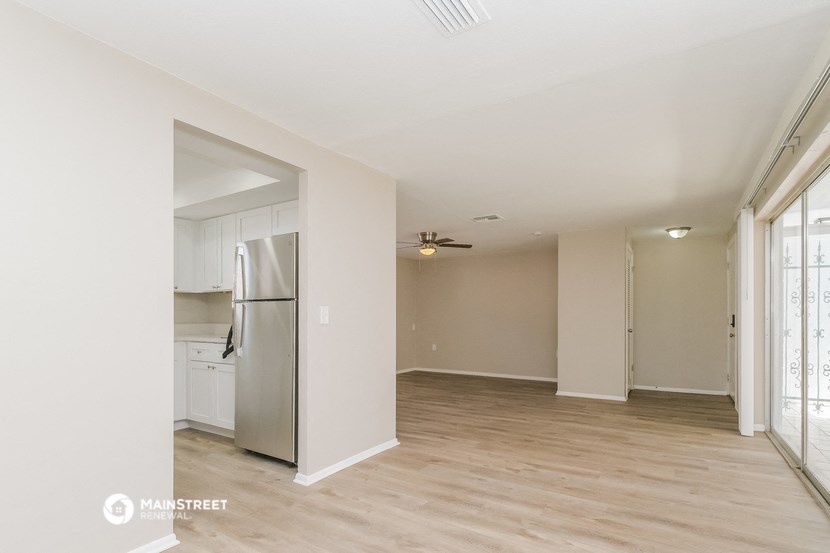 an empty living room and kitchen with a refrigerator