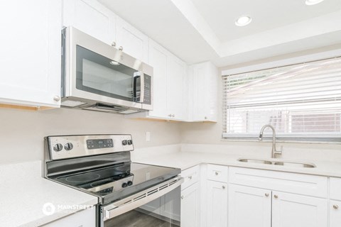a kitchen with white cabinets and a stove and a microwave