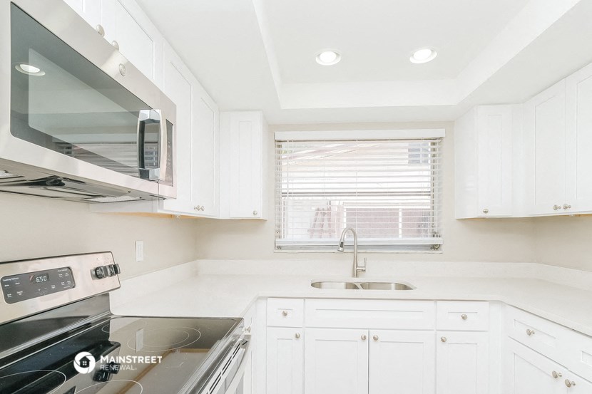 a white kitchen with white cabinets and a window