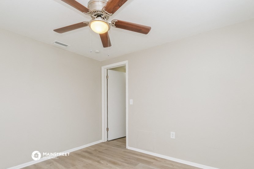 the living room of an empty house with a ceiling fan