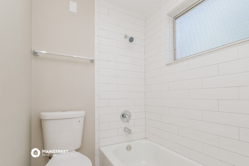 a bathroom with a toilet and a tub and a window