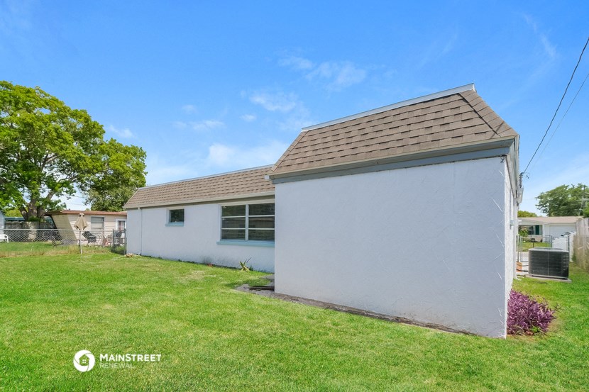 a small white house with a yard and a blue sky
