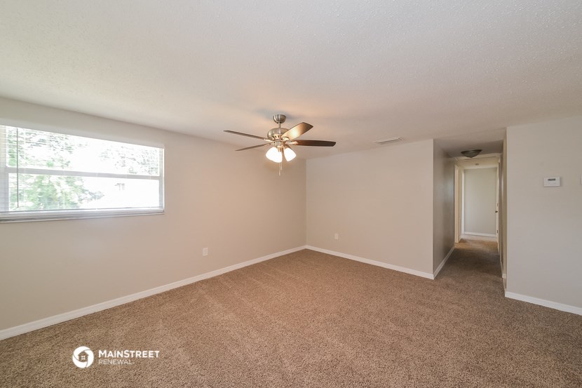 an empty living room with a ceiling fan and a window