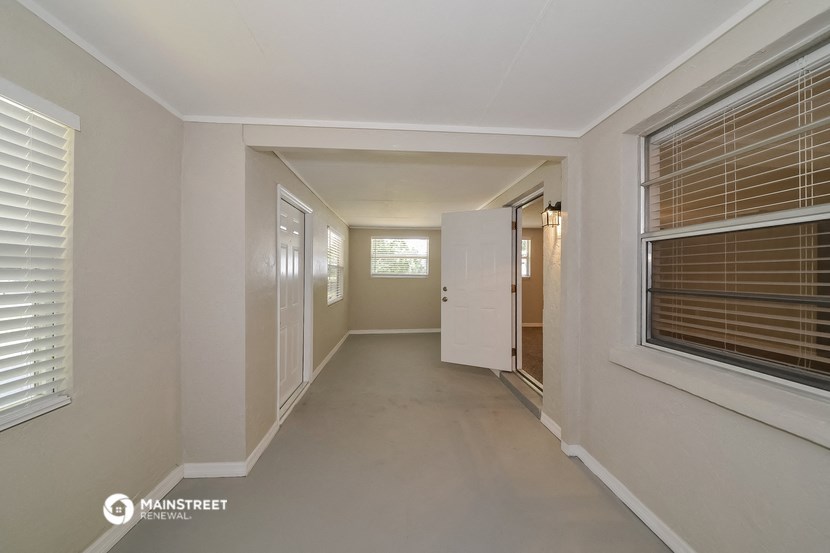 a long hallway with white walls and white blinds and a window