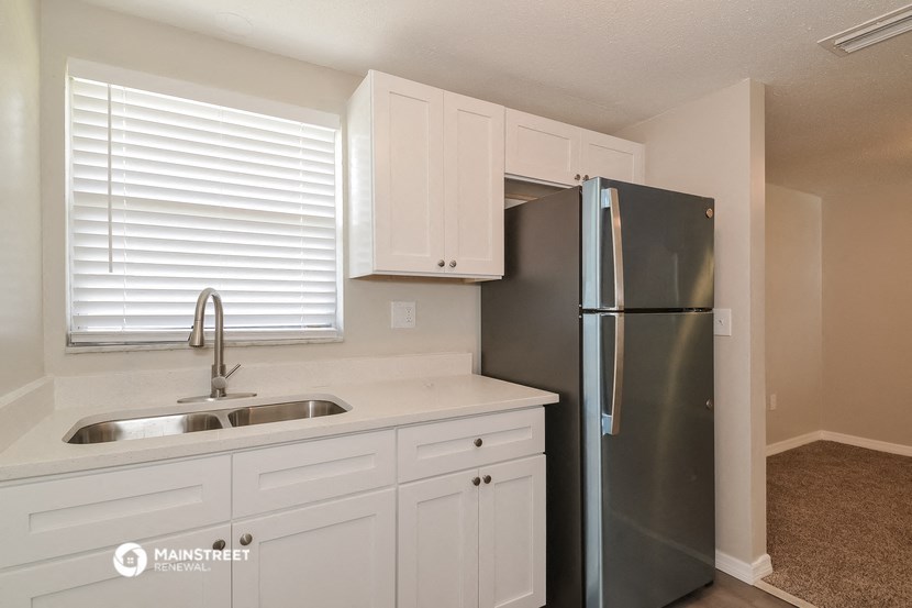 a kitchen with white cabinets and a stainless steel refrigerator