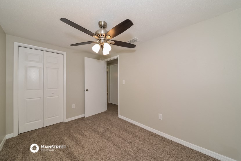 the spacious living room with ceiling fan and door to the closet