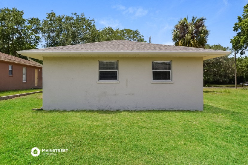 a small white house with two windows on the side of a lawn