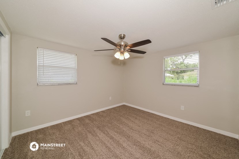 the spacious living room with ceiling fan and window