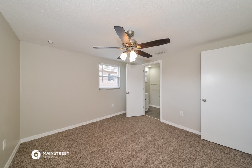 the living room is spacious and has a ceiling fan