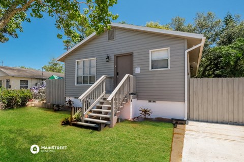 a small gray house with a porch and a staircase