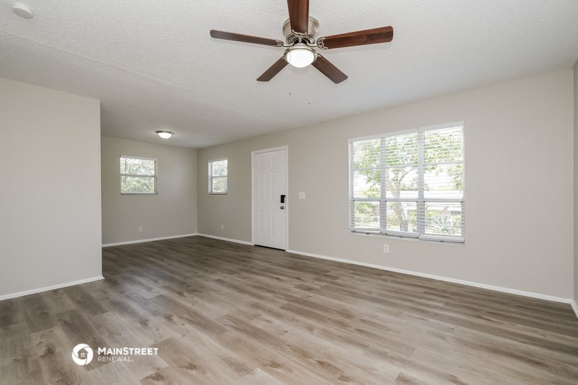 the spacious living room with wood flooring and a ceiling fan
