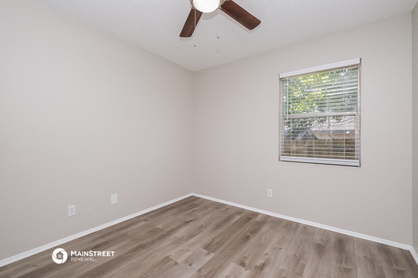 the spacious living room with wood flooring and a window