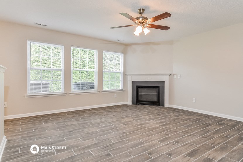 the living room with a fireplace and a ceiling fan