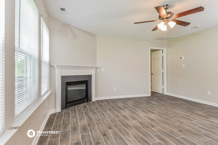 an empty living room with a fireplace and a ceiling fan