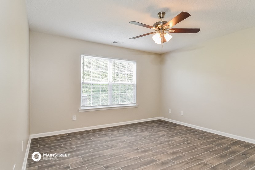 the spacious living room with wood floors and a ceiling fan