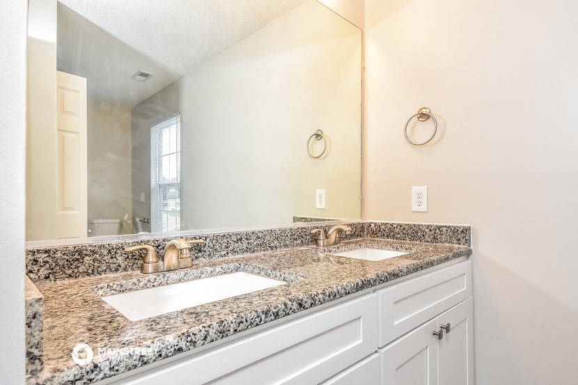 the master bathroom has dual sinks and a large mirror