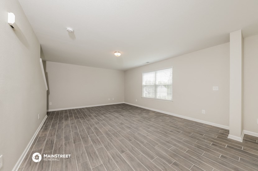 the spacious living room with vinyl flooring and a window