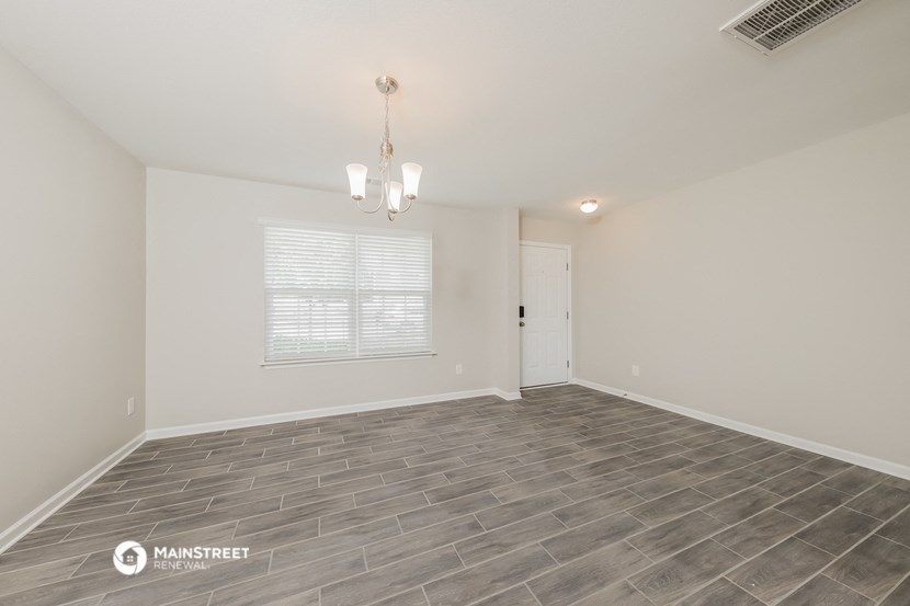 the spacious living room with wood flooring and white walls