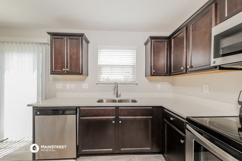 a kitchen with dark wood cabinets and a white counter top
