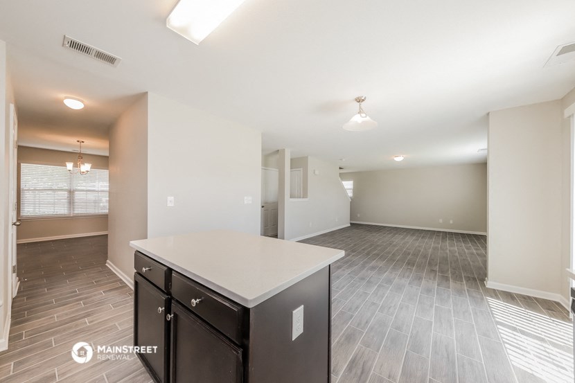 the living room and dining room of an apartment with a white counter top and a