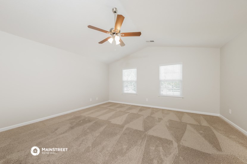 a spacious living room with carpet and a ceiling fan