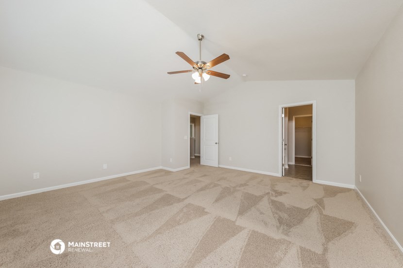 a spacious living room with carpet and a ceiling fan