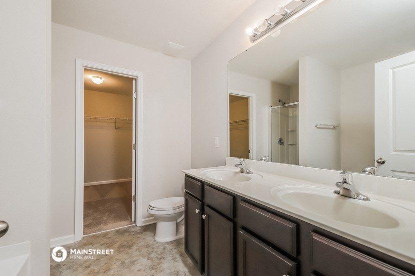 a bathroom with a large mirror and a sink and a toilet