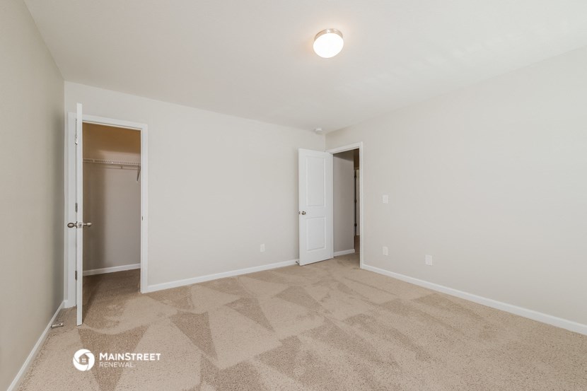 a spacious living room with carpet and a door to a closet