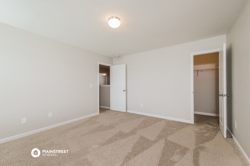 a spacious living room with carpet and a door to a closet