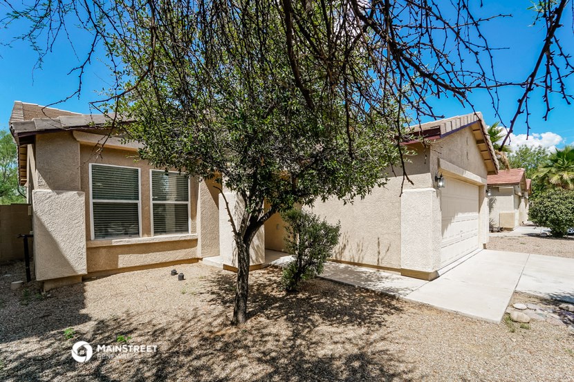 a small tan house with a tree in front of it