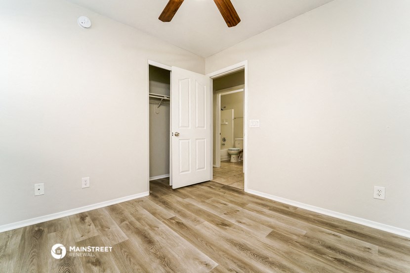 a bedroom with white walls and a door to a bathroom