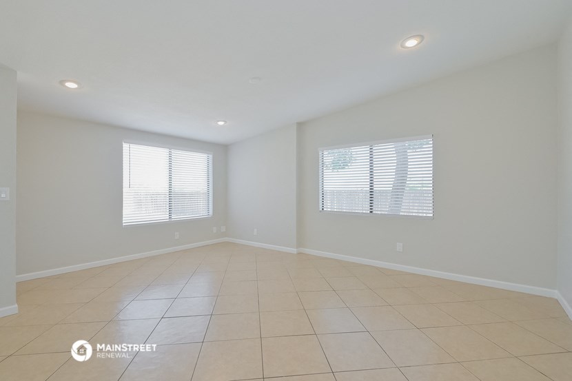 the spacious living room with tiled floors and windows