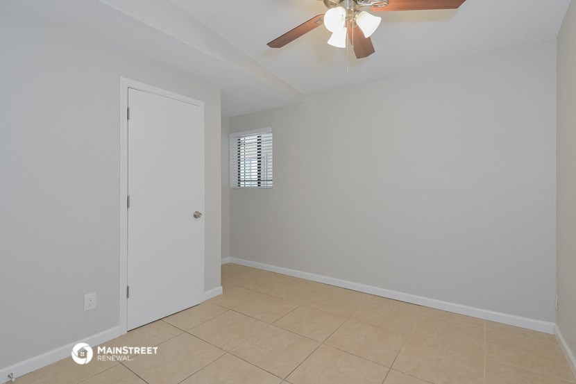 a living room with a ceiling fan and a door to a closet