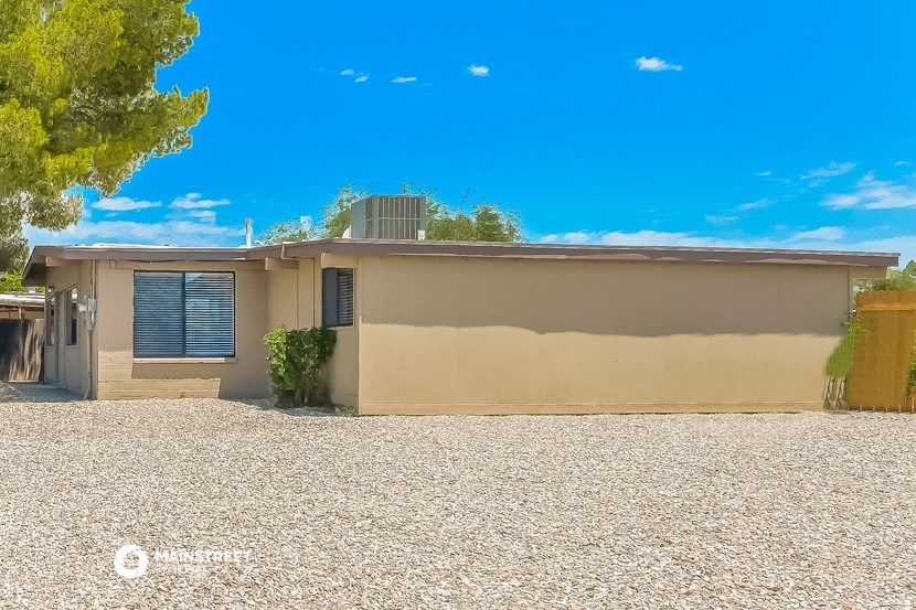 a small house with a gravel yard and a blue sky
